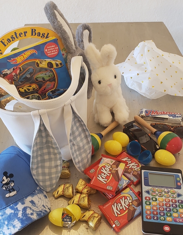 Hot Wheels cars, a bunny plush, candy, Micky hat, and a learning toy from a toddler's Easter basket