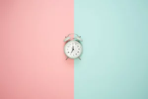 An image of an alarm clock on a pink and blue background