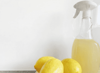 A few lemons next to a spray bottle of lemon juice on a kitchen counter