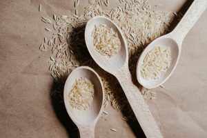 Three wooden spoons containing grains of rice
