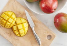 A sliced mango on a wooden cutting board