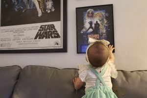 A little girl looking at framed Star Wars artwork