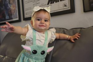 A baby girl wearing a cute Yoda outfit