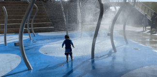A little boy enjoying a splash pad at a local playground