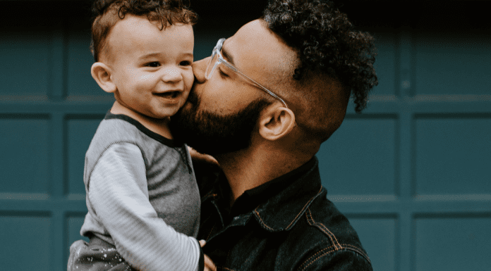 A father holding giving his toddler-aged son a kiss on the cheek