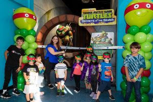 Several children participate in the ribbon cutting ceremony at Miami Children Museum's TMNT Secrets of the Sewer Exhibit