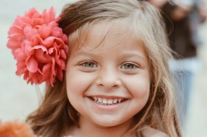 A little girl with a flower in her hair, showing off her smile