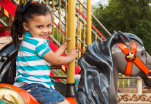 A little girl riding on a carousel at a theme park