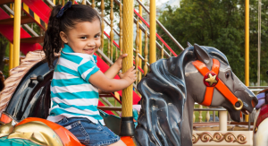 A little girl riding on a carousel at a theme park