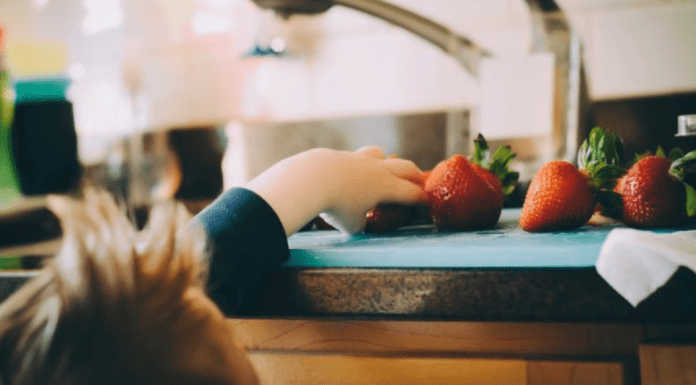 A toddler reaches to grab some fresh fruit