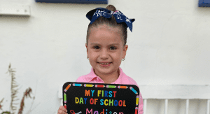 A little girl poses for a picture on the first day of school