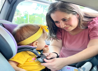 Mother strapping child in car seat