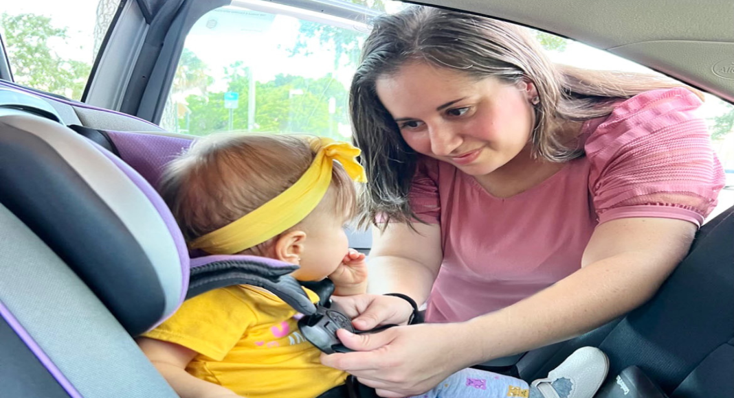 Mother strapping child in car seat