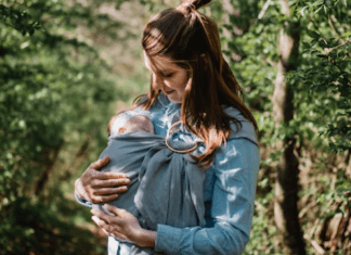 A postpartum mom wearing her newborn baby in a sling