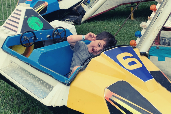 A little boy enjoying a carnival ride