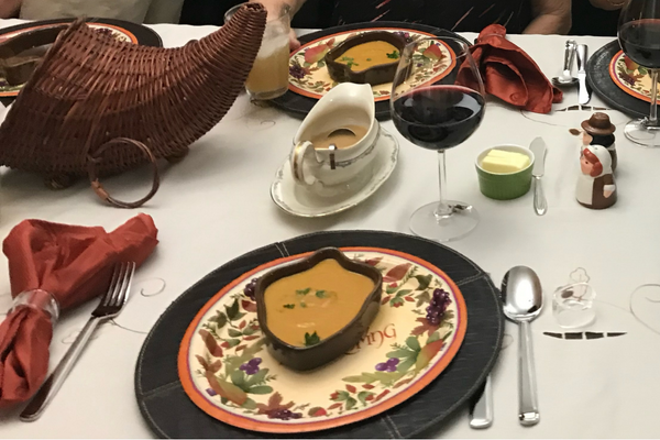 A Thanksgiving table set with acorn shaped bowls of pumpkin bisque