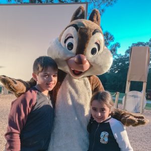 A brother and sister pose with a Disney character