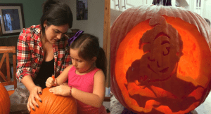 Diana helps her daughter carve a pumpkin for Halloween