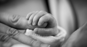 A premature infant holds onto a parent's finger