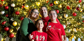 Image: A family poses for a photo in front of a Christmas Tree at Christmas Wonderland