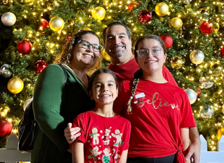 Image: A family poses for a photo in front of a Christmas Tree at Christmas Wonderland