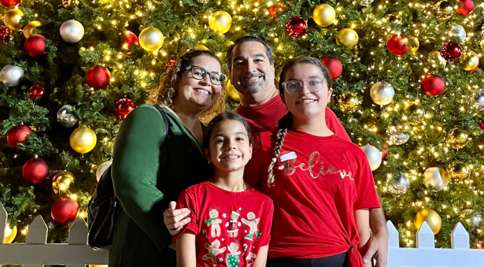 Image: A family poses for a photo in front of a Christmas Tree at Christmas Wonderland