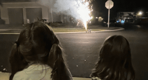Two children watching neighborhood fireworks