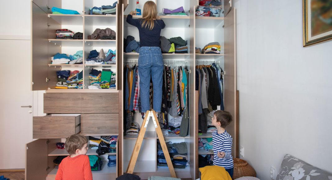 Image: A mo organizing a room while her kids play