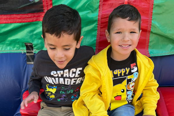 Image of two children sitting together in front of a bounce house