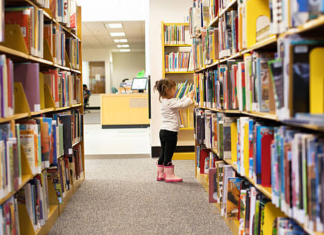 Image: A little girl peruses books at a library