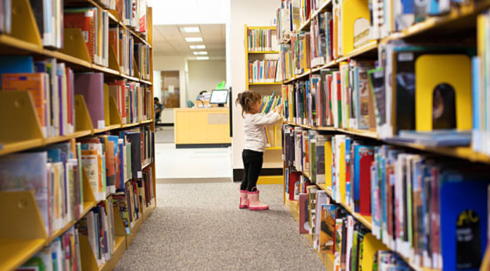 Image: A little girl peruses books at a library