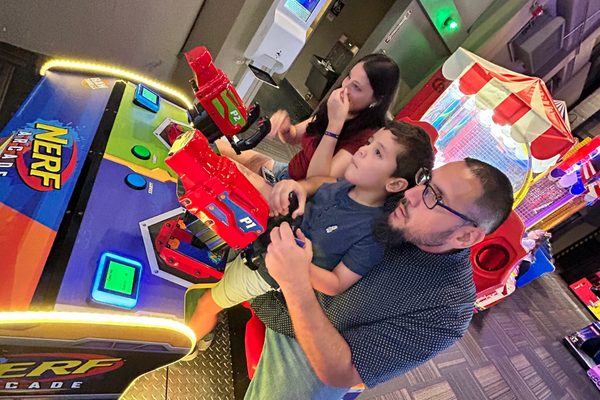 Image: A dad and his kids having fun at an arcade