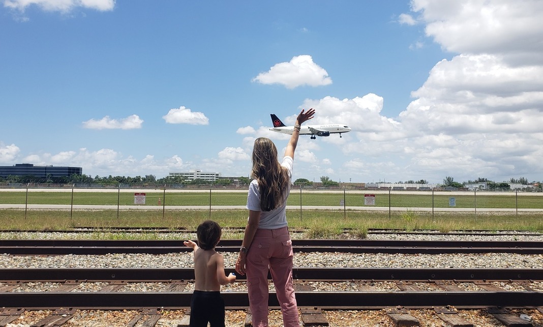Image: Sandra and her son watch and wave as an airplane lands at MIA