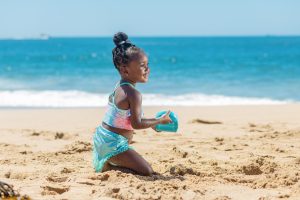 Image: A little girl playing in the sand at the beach