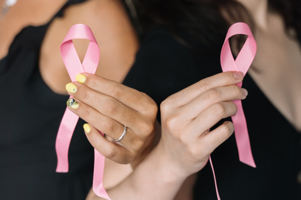 Image: Two women hold pink ribbons for Breast Cancer Awareness Month