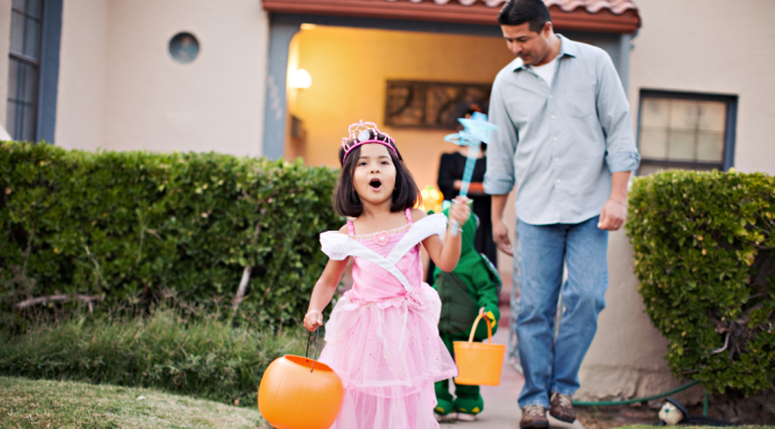 Image: A little girl trick-or-treating with her dad