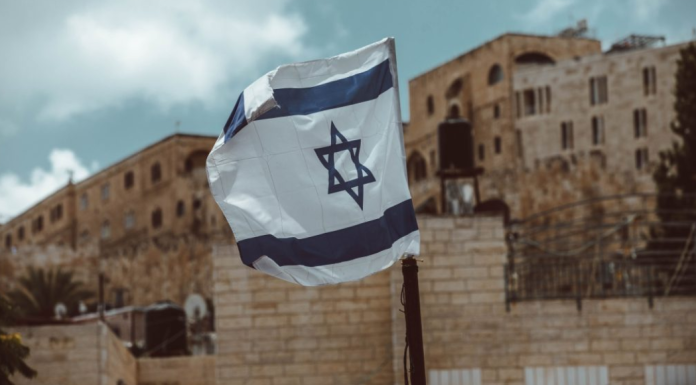 Image: An Israeli flag flies, representing the current world tragedies of war
