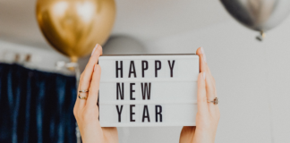 Image: Hands hold up a letter board that reads "Happy New Year"