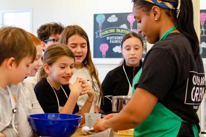 Image: A group of children participate in a cooking demonstration at Taste Buds Kitchen