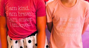 Image: Two children wearing shirts that read, "I am kind. I am brave. I am smart. I am loved."