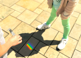 Image: Students use a prism outdoors to cast a rainbow on stone pavers