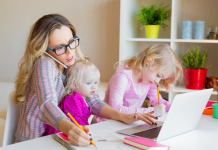 Image: A working mom trying to work from home with a toddler on her lap and a preschooler next to her