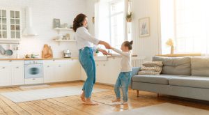 Image: A mother dances with her young daughter in their living room