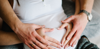 Image: Expectant parents place their hands on the mother's belly in the shape of a heart