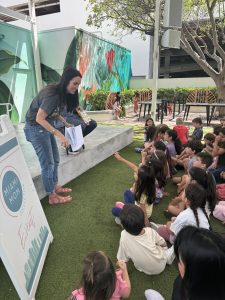 Image: Comic Kids founder Kat Kat Barrow-Horth shares a picture book with children at a recent Miami Mom Collective event