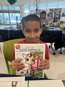 Image: A child holds a drawing book he received from Comic Kids and Miami Mom Collective