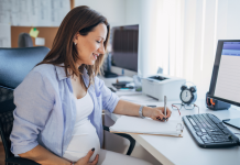 Image: An expectant mother sits at her desk at work