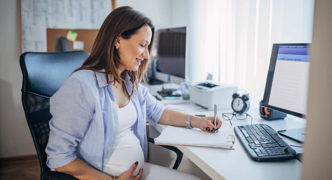 Image: An expectant mother sits at her desk at work