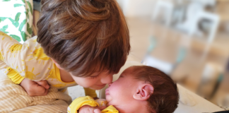 Image: A little boy looks lovingly at his newborn brother