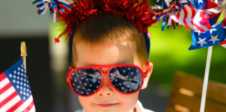 Image: A child wearing 4th of July themed sunglasses and holding flag-themed props